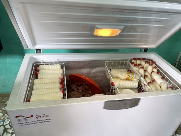 A fridge with an open top, containing many bottles of milk.